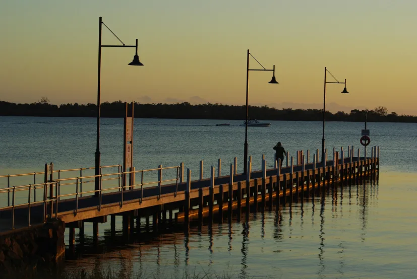 A jetty reaching into still water at dusk